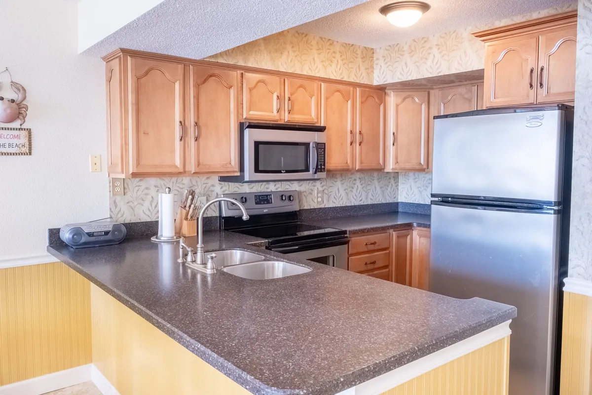 This image features a spacious kitchen island, sleek stainless steel appliances, and warm wooden cabinetry—all elements that speak to the kitchen’s modern setup. The open layout suggests a space designed for cooking and entertaining, aligning with the section’s emphasis on social connection and culinary experiences.