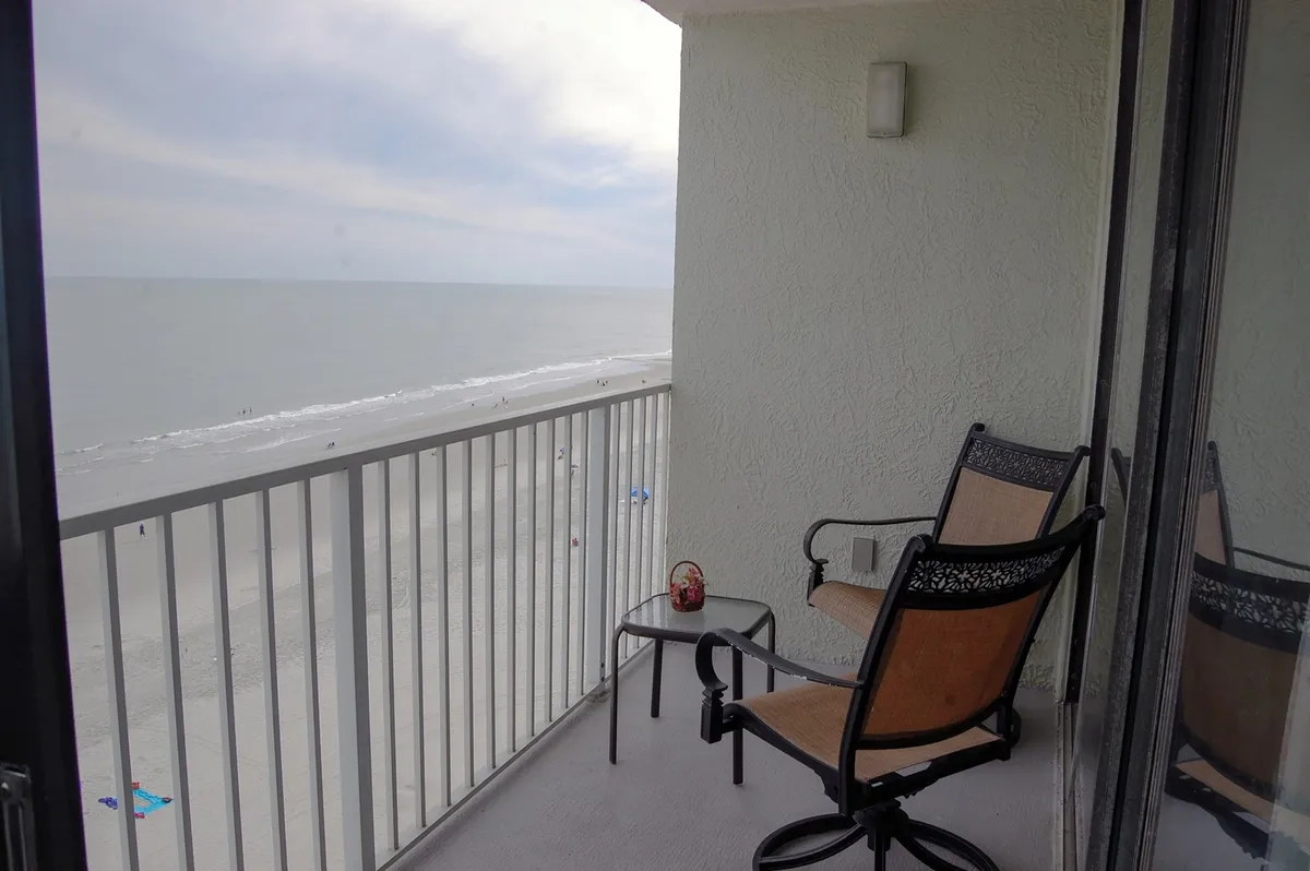 This exterior shot highlights the private balcony, featuring comfortable seating and a small table overlooking the Atlantic. The scene is serene, with calm ocean views and a gentle ambiance ideal for morning coffee or quiet contemplation.